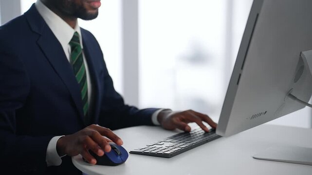 オフィスでデスクトップPCを使って作業する黒人男性ビジネスパーソン