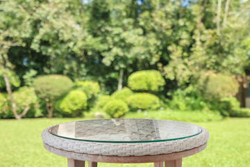 Obraz premium Empty round glass table top with abstract blur green park garden background