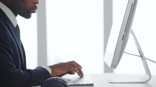 オフィスのデスクでPCを使って作業する黒人男性ビジネスパーソン