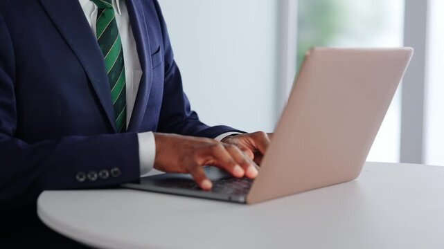 オフィスでノートパソコン使って作業する黒人男性ビジネスパーソンの手元