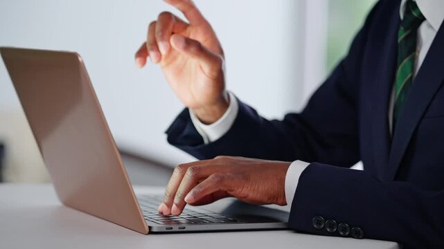 オフィスでノートパソコン使って作業する黒人男性ビジネスパーソンの手元