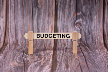 Fototapeta premium Budgeting symbol. A wooden stick clasped by clothespins set over a beautiful Brown Grunge Wooden Texture Background. Business and Budgeting concept with copy space