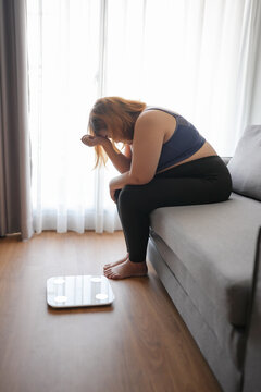 Sad woman with fat upset bored of dieting Weight loss fail&nbsp; Fat diet and scale sad asian woman on weight scale at home weight control.