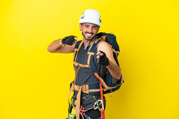Fototapeta premium Young caucasian rock climber man isolated on yellow background pointing to the front and smiling