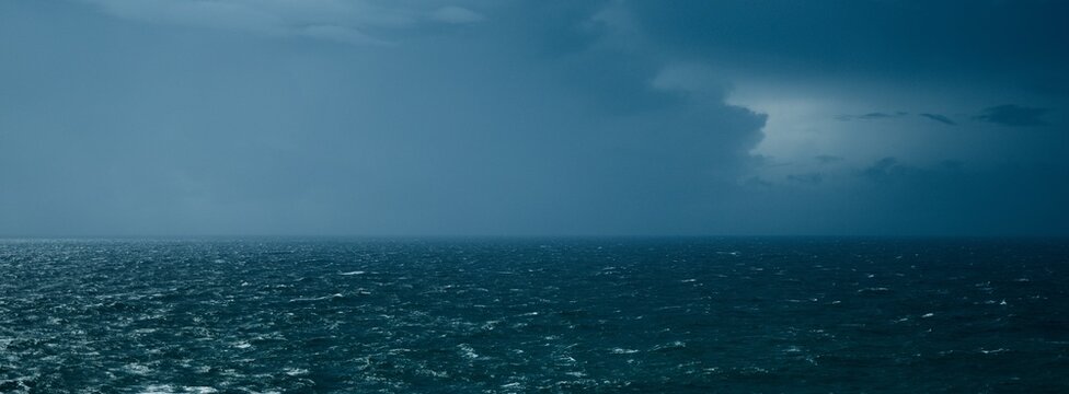 Vast Moody Ocean Horizon with Choppy Dark Blue Water Under a Dramatic Stormy Sky - Wide Panoramic Seascape Background