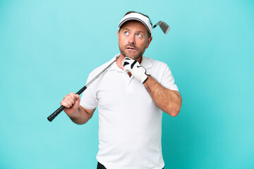 Naklejka premium Middle age caucasian golfer player man isolated on blue background and looking up