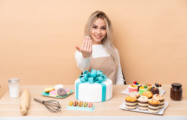Teenager pastry chef with a big cake in a table inviting to come
