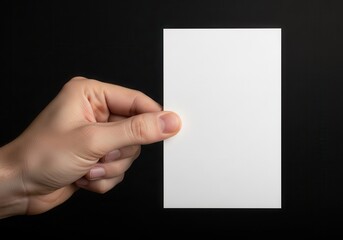 Male hand firmly holds blank rectangular white card against dark background