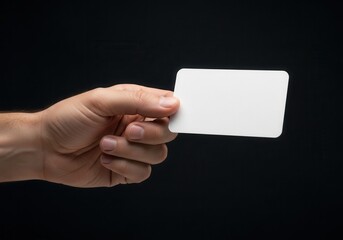 Male hand holds blank white rectangular card against dark background