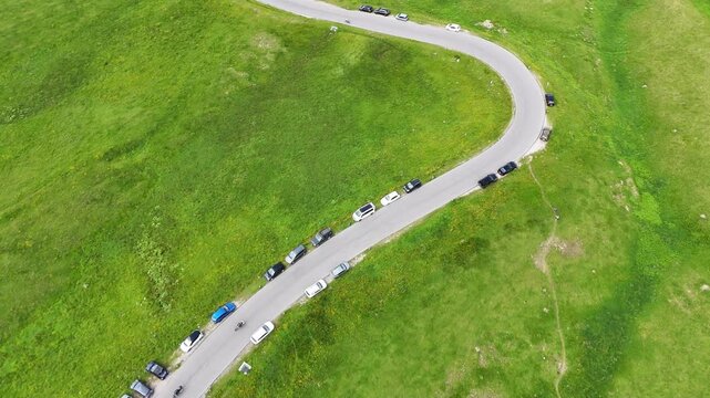 Passo Giau, Giau pass Italy, dolomites. Drone flight, view on winding road on mountain pass below. Some cars are driving on the widing road in the Italian Dolomites. Alpine meadows. Wild nature. Sunny
