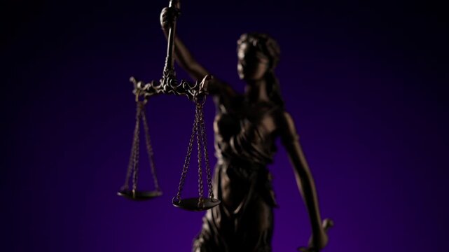 Rack focus shot slowly revealing the bronze statue of Lady Justice holding the scales of truth against a dark purple background.