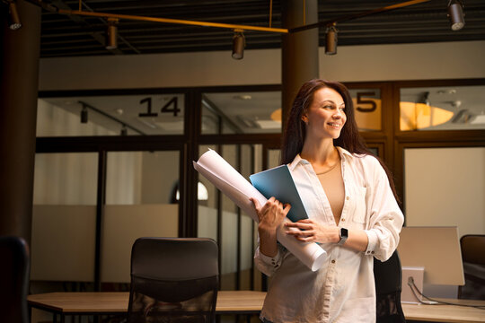 Smiling woman with drawings and folders in a conference room
