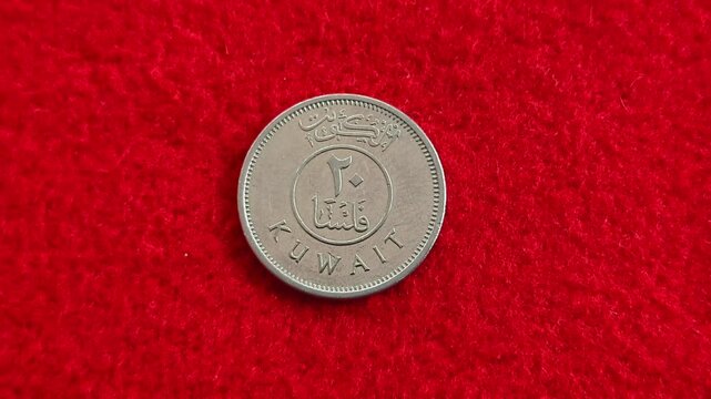 Different kuwaiti fils round metal coin isolated on red background with copy space. Extreme closeup macro top view. Economy, trade, recession, inflation, savings and forex concept.