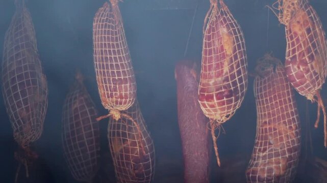 Smoking and curing meat using traditional methods in smokehouse.