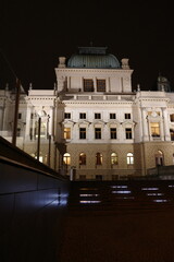 Naklejka premium A stately building stands illuminated at night. Architectural details are visible. Windows reflect light. A dome crowns the structure. The facade appears grand. The scene conveys elegance