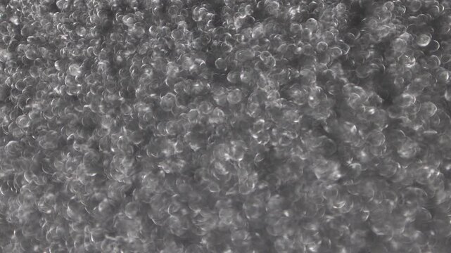 Abstract out-of-focus shot of a shimmering platinum surface glowing with a dense field of soft silver bokeh circles