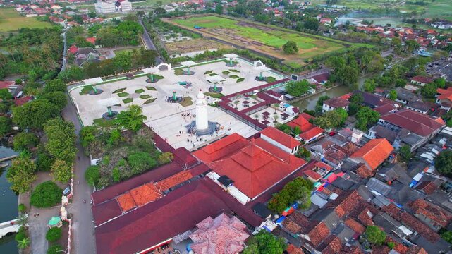 Aerial drone footage of the Agung Banten old mosque, and the square place, at sunset time, main red roof, with the characteristic white minaret, in Serang area, Banten regency, Java island, Indonesia