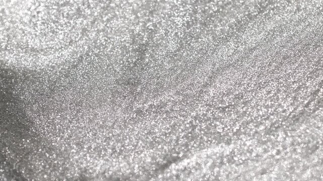 Detailed rotating close-up of bright silver paint specialized sandy texture and radiant glitter particles on surface