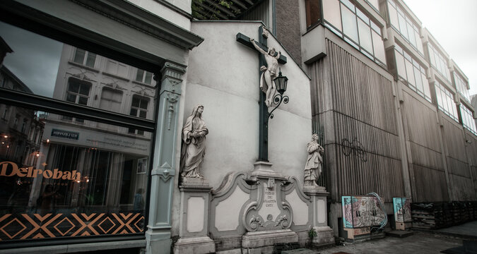 Religious monument beside storefront on September 10, 2025 in Leuven, Belgium