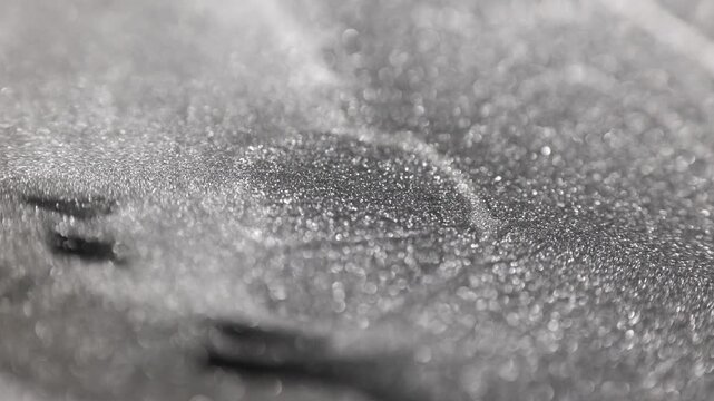 Static shimmering macro shot of a titanium paint surface with shallow depth of field highlighting the glittering sandy texture and ridges