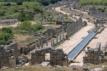 Obraz premium View from the hill to the ruins of the ancient city of Perga. An ancient city located in Turkey. Columns and a water channel in an ancient city. History and culture of ancient civilizations.