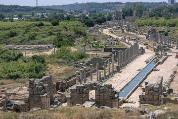 View from the hill to the ruins of the ancient city of Perga. An ancient city located in Turkey. Columns and a water channel in an ancient city. History and culture of ancient civilizations.