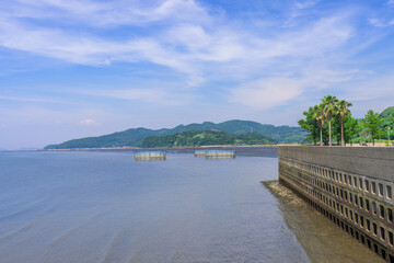 Obraz premium 青空を背景に 「潮風が運ぶ、防波堤から見える海と遊歩道」 宇土市観光スポット(宇土マリーナおこしき館) With a blue sky as a backdrop 