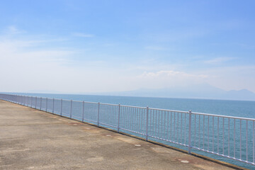 Obraz premium 青空を背景に 「潮風が運ぶ、防波堤から見える海と遊歩道」 宇土市観光スポット(宇土マリーナおこしき館) With a blue sky as a backdrop 