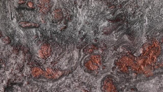 Macro close-up of dark titanium and copper metallic paint slowly flowing and mixing to create abstract patterns with specialized sandy texture and radiant glitter particles shifting 
