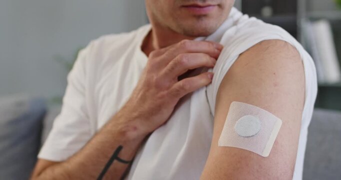 Man points at sensor patch for diabetes. Wearable monitor on the upper arm tracks glucose and supports better health management. Doctor prescribed device. Concept: smart wearable diabetes care.