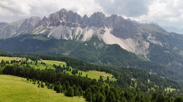 Forward drone flight, cinematic, bird view in impressive Italian Dolomites, fresh green meadows with beautiful pine trees. Amazing wilderness, Aferer Geisler, Odle Eoresin background. Environment, tra