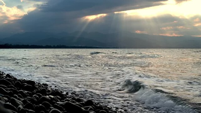 Dramatic Mediterranean sunset glowing over Cyprus rocky coastline. Golden hour seascape, waves reflecting warm orange light.

