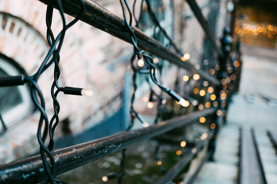 Charming Festive String Lights Elegantly Draped Over Rustic Urban Balcony Railing Creating Warm Ambiance