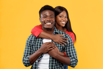 Naklejka premium A man and woman stand close together, smiling widely. The man has short hair and wears a checkered shirt, while the woman has long hair and wears a red top. They both appear happy.