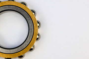 Obraz premium Top view of a precision industrial steel ball bearing with a golden brass cage isolated on a white background with copy space