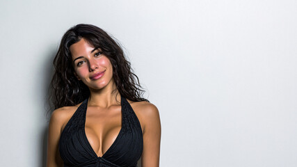 Naklejka premium beautiful brunette woman with curly hair in black top, sexy glamorous female model posing on white background, stunning attractive woman with long curly hair and elegant outfit