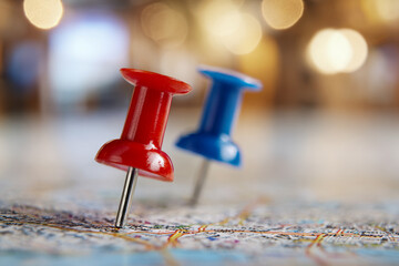 Red and blue pins marking specific locations on a detailed city map with soft bokeh lights in the background creating a warm ambiance