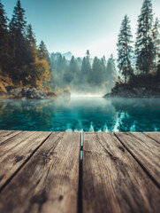 Fototapeta premium Wooden pier overlooking a misty forest lake with clear blue water surrounded by evergreen trees under a clear sky in early morning light
