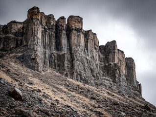 Impressive rugged cliff formation with steep rocky slope under overcast sky in a barren mountainous landscape