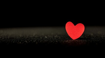 Obraz premium devotion. Minimalist red heart on a textured black surface, symbolizing love and gratitude. wellbeing guides, coaching materials, designed for mental health education and mindfulness programs. 