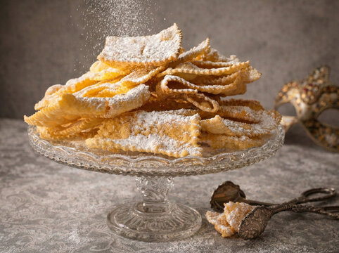 Traditionelles italienisches Faschingsgeb&auml;ck Chiacchiere mit Puderzucker auf Kristallteller