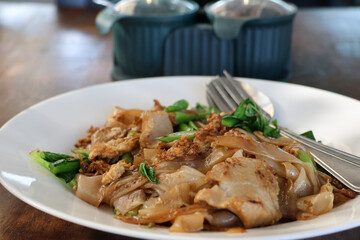 Fototapeta premium Stir-fried soy sauce noodles with pork , fresh vegetable, served on a clean white plate