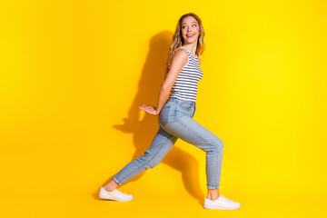 Young stylish female posing cheerfully against yellow backdrop in casual attire for lifestyle...
