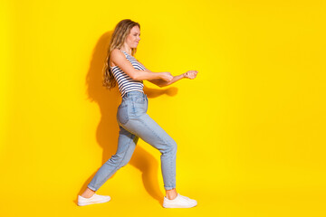 Fashionable young woman posing dynamically in trendy casual outfit against a vibrant yellow...
