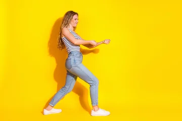 Fotobehang Onderzeeër Fashionable young woman posing dynamically in trendy casual outfit against a vibrant yellow background  © deagreez