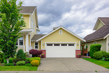 A perfect neighbourhood. Family house with wide garage door and concrete driveway in front