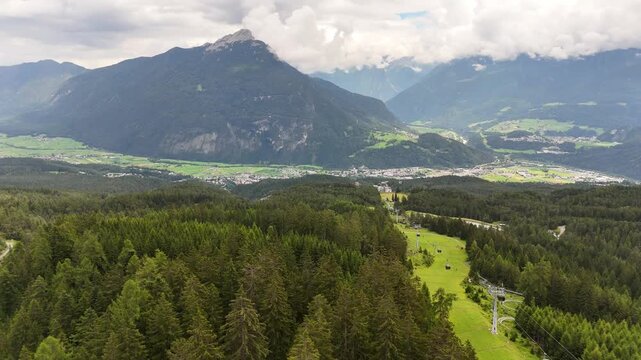 22 july 2024, Imst, Austria. Forward drone flight at ski slope in summer, view on Imst city in Gurgeltal valley and Tschirgant mountain in background. Cloudy summer day. Beautiful travel destination. 