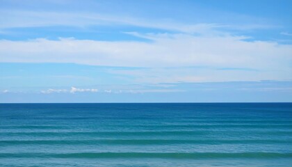 Obraz premium A serene seascape showcases a vibrant blue sky with wispy clouds meeting the deep blue horizon of the ocean on a bright day