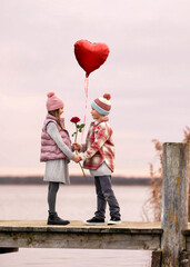 lovely boy gives a red rose and red heart balloon to his girlfriend