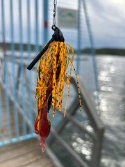 Fototapeta premium Fishing lure hanging over lake waters from a dock